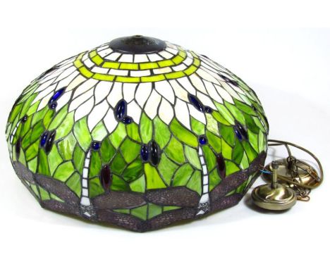 A decorative lamp shade, set with a repeat pattern of dragonflies and flowers, predominantly in green, cream and blue with le