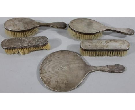 A George VI silver five piece dressing table set, comprising a hand mirror, 26cm high, two hairbrushes and two clothes brushe