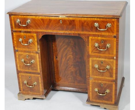 A George III mahogany and satinwood kneehole desk, the rectangular moulded overhanging top raised above a frieze drawer and s