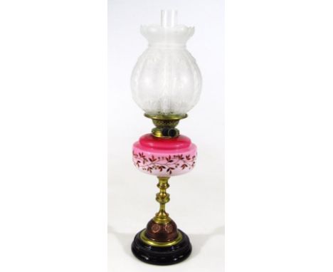A Victorian pink glass overlay and brass oil lamp, with clear funnel, elaborate glass shade raised with scrolls and flowers, 
