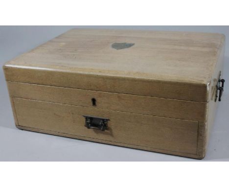A light oak canteen, the hinged lid centred by a brass cartouche with fitted interior above a frieze drawer, a further baize 