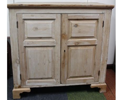 A pine freestanding cupboard, the overhanging rectangular top above two panelled doors hinging to reveal a part fitted interi
