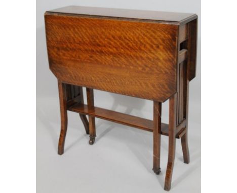 An Edwardian oak Sutherland table, with gateleg action and canted top on square supports terminating in castors with a lower 