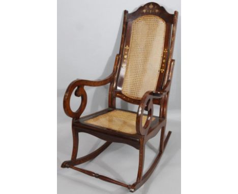 A modern hardwood rocking chair, with floral inserts, bergere back and (removable) cushion seat, with heavy scroll arms raise