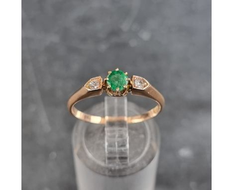 A yellow metal emerald and diamond three stone ring, stamped '585', size Q. 