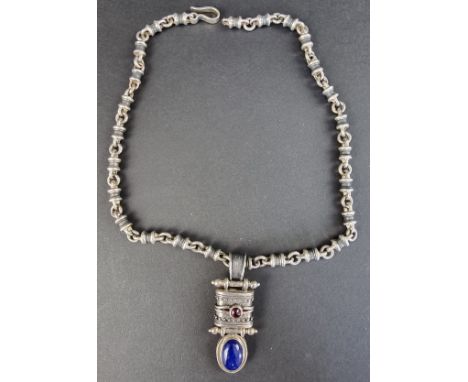 A South American white metal pendant, set cabochon lapis lazuli and garnet, on a white metal tubular and ring chain, with hoo