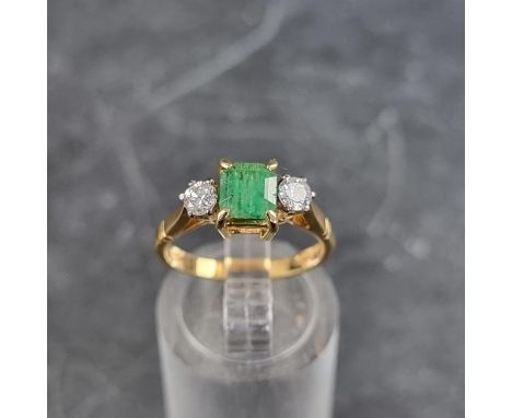 An 18ct gold emerald and diamond three stone ring, London 1977, size K 1/2, gross weight 3.3g. 