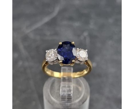 A modern 18ct gold diamond and sapphire three stone ring, set central oval sapphire with a brilliant cut diamond to each side