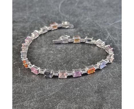 A white metal multicoloured sapphire and diamond set bracelet, stamped 750, having twenty octagonal step cut sapphires, of ap