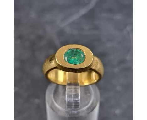 A yellow metal emerald solitaire ring,&nbsp;in a rub over setting, size M, unmarked. 