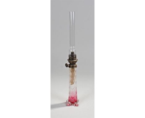 Slender glass oil lamp, the glass chimney above a brass fitting, clear to red glass base, 46cm high