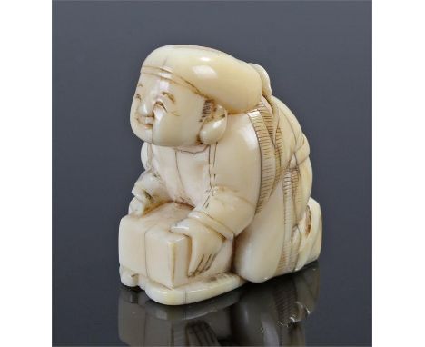 Meiji period ivory netsuke, carved as a figure crouched over a box, 37mm high