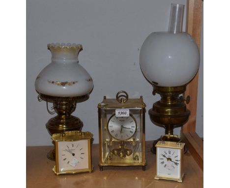 A Kundo quartz torsion clock, brass case with four glass panels; others, a Rapport carriage clock, etc; a brass oil lamp, etc