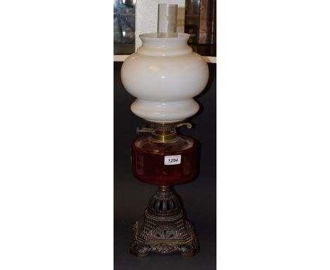 A Victorian brass oil lamp, opaque white glass shade, cranberry glass reservoir, twin burner, cast iron base, 58cm high overa