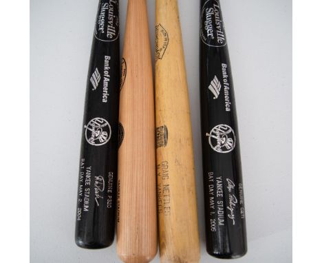 A set of four Yankee-themed baseball bats, including three Louisville Sluggers, two in black with silver accents from Bat Day