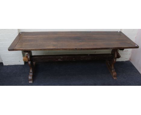 A 19th century elm refectory dining table, the cleated plank top raised on shaped end supports and sledge feet, united by a p