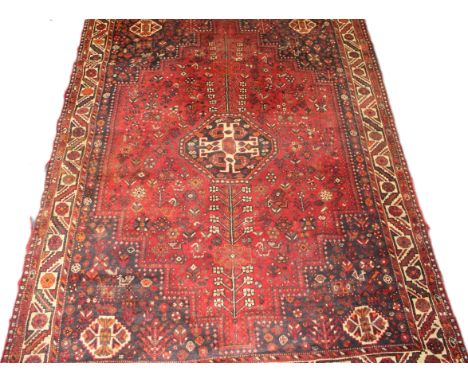 A Shiraz carpet, woven with a central lozenge pole medallion on a busy madder ground, 290 x 210cm
