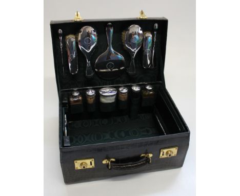 A good crocodile skin and silk travelling case having silver mounted dressing table and travelling fittings and outer cover, 