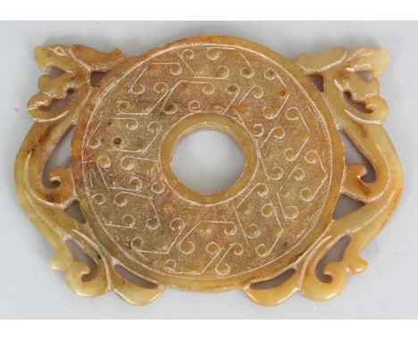 A CHINESE ARCHAIC STYLE JADE-LIKE BI DISC, of circular form within two relief carved dragons, 5in wide at widest point & 3.75