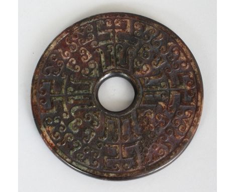 A CHINESE JADE-LIKE CIRCULAR BI DISC, decorated in shallow relief with archaic designs, 4.75in diameter.