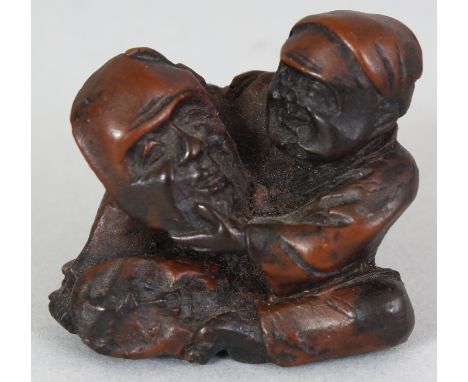 A JAPANESE MEIJI PERIOD WOOD NETSUKE OF A MASK MAKER, unsigned, the seated man examining a mask, 1.25in wide & 1.25in high.