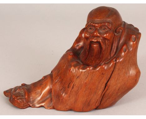 A GOOD QUALITY 19TH CARVED ROOTWOOD FIGURE OF A RECLINING SAGE, wrapped in a well grained cloak, 6.25in long & 4.6in high.