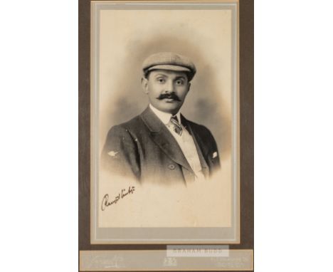 Signed b&w photograph of portrait of cricketer K.S. Ranjitsinhji, posed in a studio setting wearing a cap, jacket and tie. Si