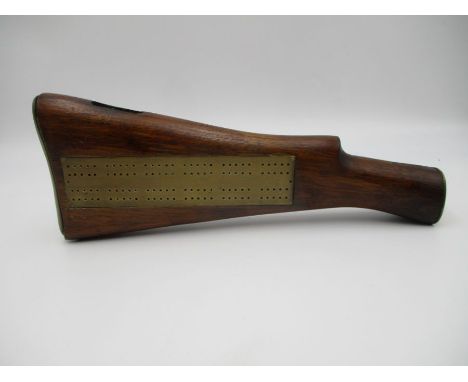 A brass cribbage board inserted into a stock of shotgun