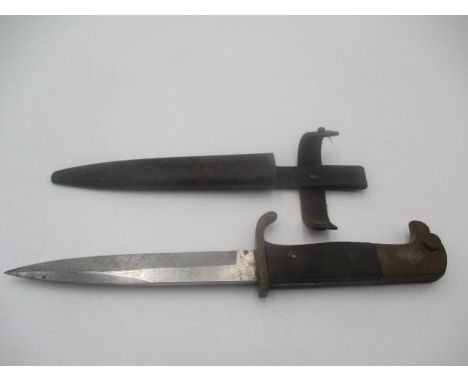 A German WWII dagger with eagle head handle over black chequered grip in metal scabbard