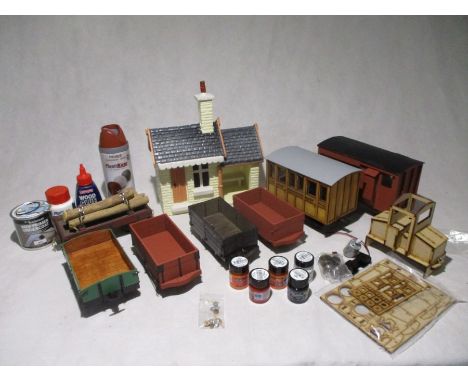 A collection of garden railway including a coach, several wagons, station building, spare parts and accessories (paint, glue 