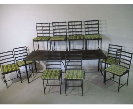 A large rustic metal garden table with ten matching chairs