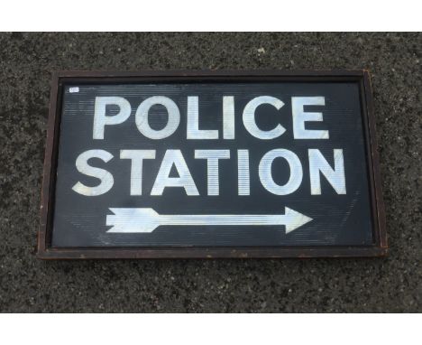 An early rectangular reflective glass sign - "Police Station" with arrow pointing right, set within a wooden frame.
