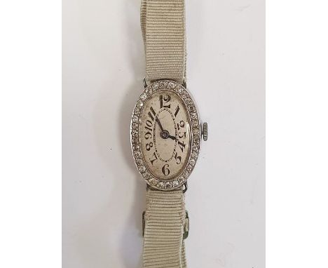 A 1920s platinum and diamond lady's wristwatch on fabric strap, oval with Arabic numerals and an oval and mother of pearl loc
