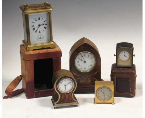 A brass carriage clock with travelling case, a miniature clock with travelling case, a gothic arched wooden mantel clock, a b