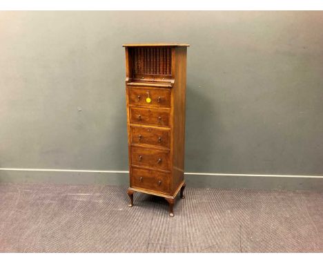 A narrow walnut chest, early 20th century, the rectangular top over a faux book panel frieze revealing a compartment over two