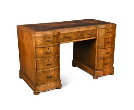Attributed to Heal's, an Art Deco oak kneehole desk,  the leather inset top with central frieze drawer flanked by four gradua