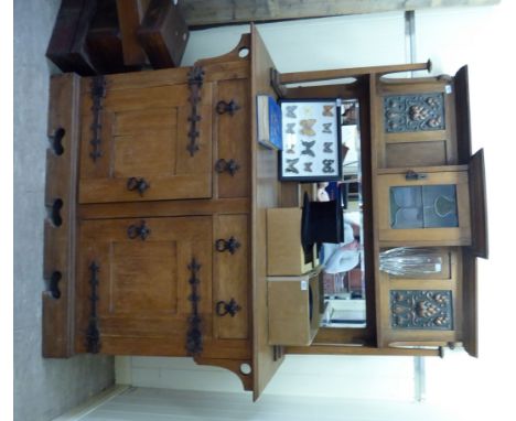 An early 20thC Arts & Crafts inspired light oak dresser, the superstructure comprising a high, bevelled mirror back, a centra