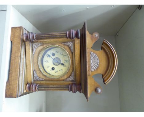 An early 20thC walnut cased mantel clock with an arched crest and pilaster flanks, on a plinth; the gong strike movement face