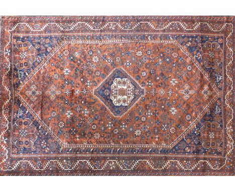 A South West Persian Qashqai carpet, central diamond medallion with repeating petal motifs on a terracotta field, within styl