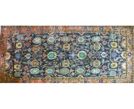 A 20th century Iranian carpet with repeating floral motifs, on a blue ground, contained by floral border, 334 x 162cm 