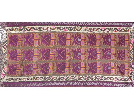 A 20th century Kelim carpet with repeating geometric purple motifs, contained by geometric border, 310 x 148cm 