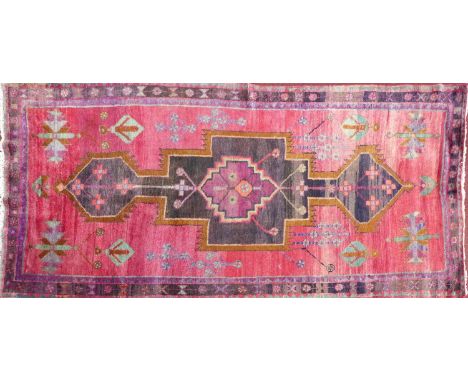 A Persian carpet with large geometric medallion, on a rouge ground, contained by geometric border, 270 x 140cm 