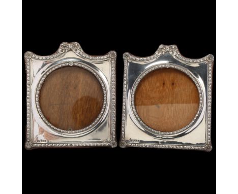 A pair of Edwardian silver-fronted photo frames, Robert Pringle & Sons, Birmingham 1905, shaped form with circular apertures 