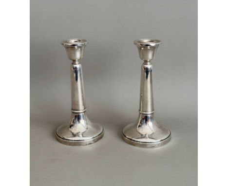 A pair of George V silver candlesticks - Sanders &amp; Mackenzie, Birmingham 1923, of plain, turned form with urn nozzles and