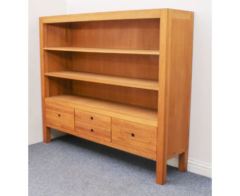 A matching modern light-oak bookcase - with three open shelves over four drawers with pierced circular handles, on stile feet
