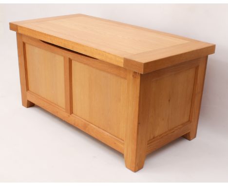 A modern light-oak blanket box - the cleated top opening on cantilvered hinges, over a two-panel front and panelled sides, on