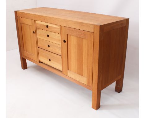 A modern light-oak side cabinet or sideboard - with two cupboards flanking a central bank of four graduated drawers, all with