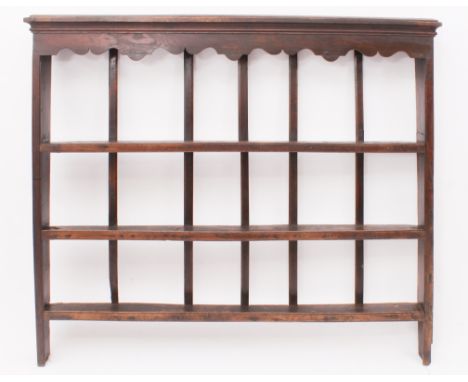 An 18th century oak Delft rack - with cavetto cornice over a shaped frieze and three open shelves with a slatted back. (LWH 1