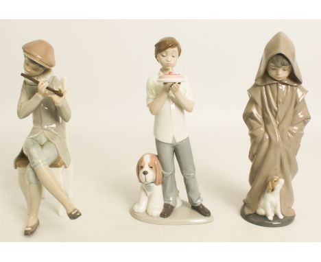 One Lladro and two Nao figurines - a seated boy playing the flute (20 cm high), a boy holding a cake with his dog beside him 