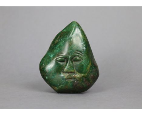 A polished green stone boulder carved with a face, 5½” high.